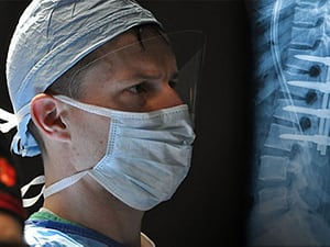 Dr. Herzog in a surgical mask looking at a spine x-ray